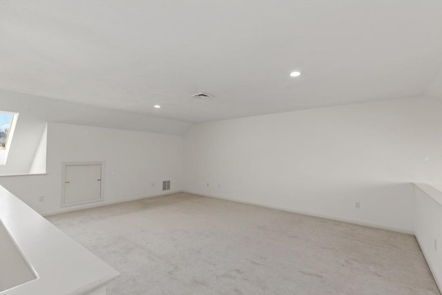 additional living space featuring lofted ceiling with skylight, light colored carpet, and visible vents