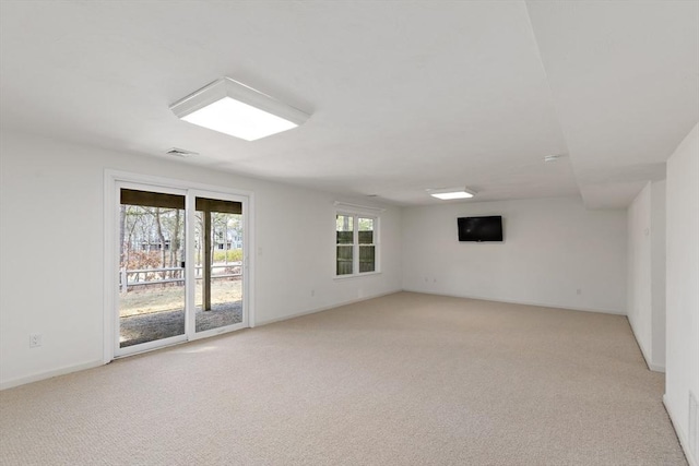 spare room featuring visible vents, light colored carpet, and baseboards