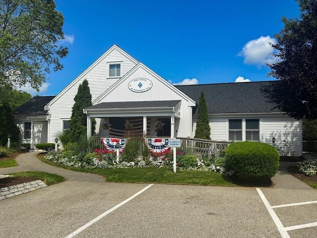 view of front facade with uncovered parking and a shingled roof