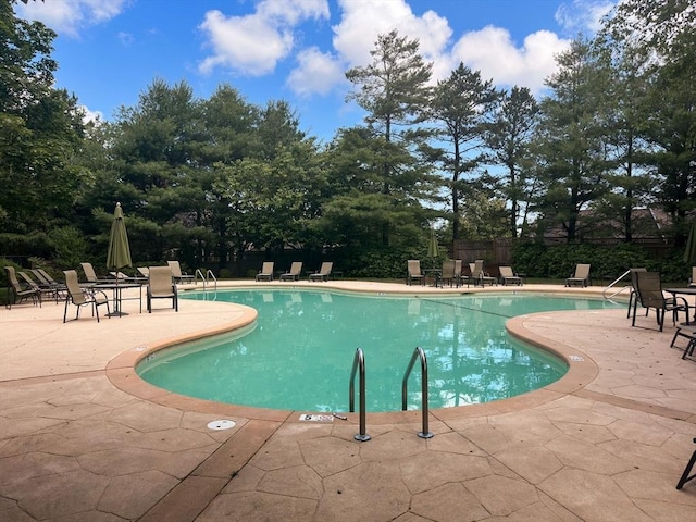 community pool with a patio area and fence