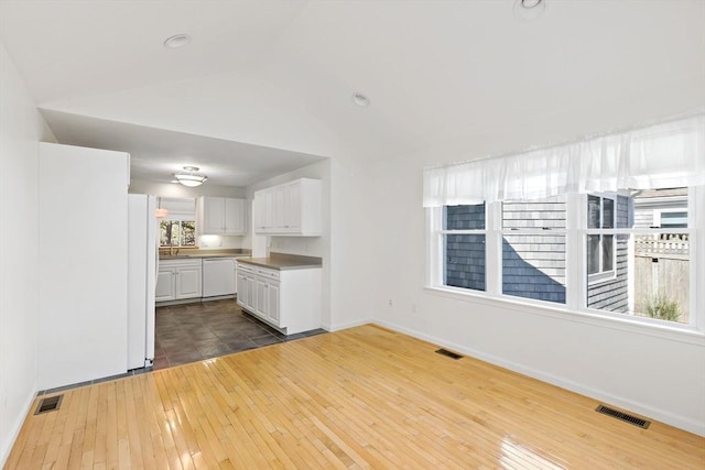 interior space with dark wood finished floors, lofted ceiling, and visible vents