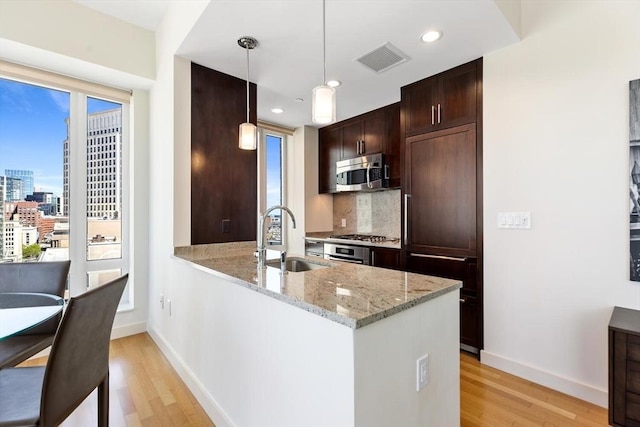 kitchen with visible vents, a sink, baseboards, stainless steel appliances, and light wood-style flooring