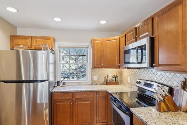 kitchen with light stone countertops, appliances with stainless steel finishes, and tasteful backsplash