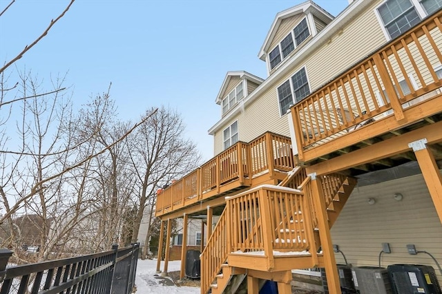 snow covered rear of property featuring a wooden deck and cooling unit