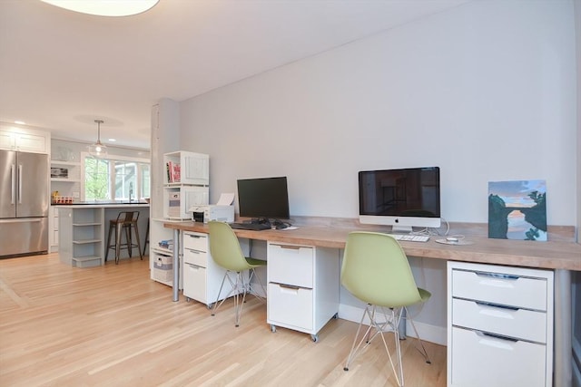 office with light wood-type flooring and built in desk