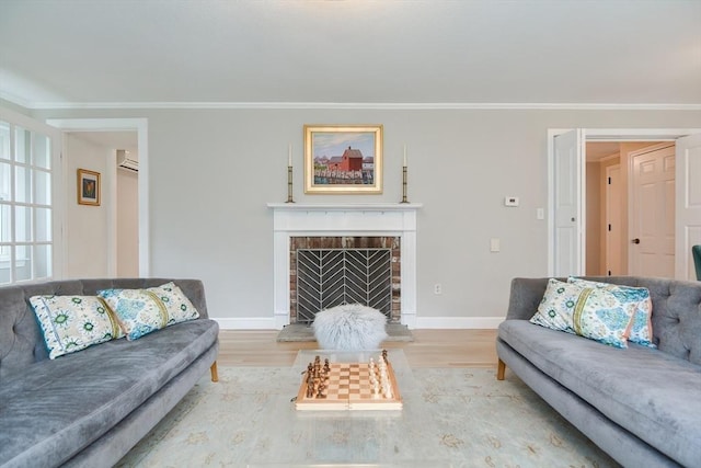 living room featuring wood finished floors, ornamental molding, a brick fireplace, and baseboards