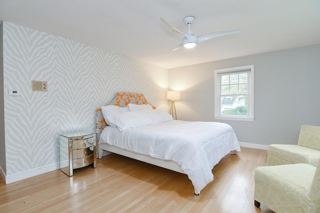 bedroom with wallpapered walls, baseboards, an accent wall, light wood-style flooring, and ceiling fan