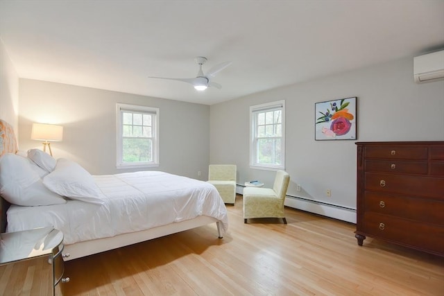 bedroom with baseboard heating, multiple windows, and light wood finished floors