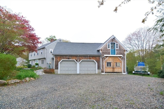 view of front of house featuring a garage, driveway, a shingled roof, and a chimney