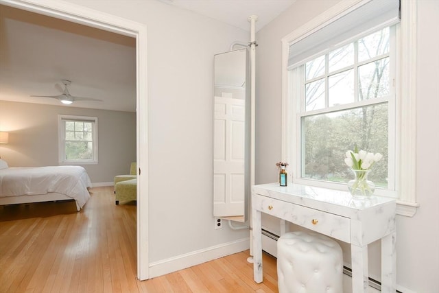 bedroom with light wood-type flooring, baseboards, and baseboard heating