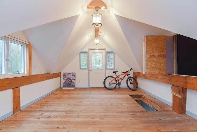 bonus room featuring healthy amount of natural light, hardwood / wood-style flooring, vaulted ceiling, and baseboards