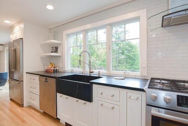 kitchen with appliances with stainless steel finishes, a sink, plenty of natural light, dark countertops, and recessed lighting
