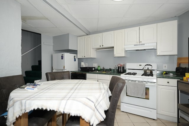 kitchen with white appliances, a paneled ceiling, light tile patterned floors, and white cabinets