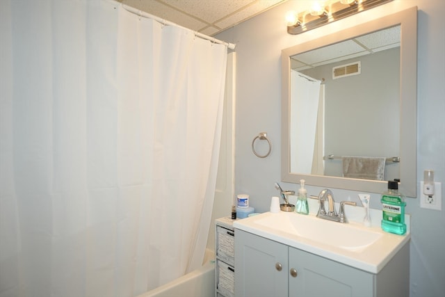 bathroom with shower / tub combo with curtain, a drop ceiling, and vanity