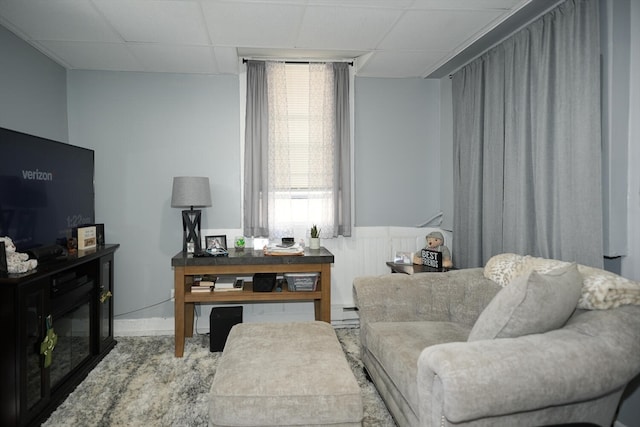 living room with baseboard heating and a paneled ceiling