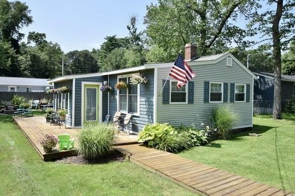 rear view of property with a chimney, a wooden deck, a yard, and fence