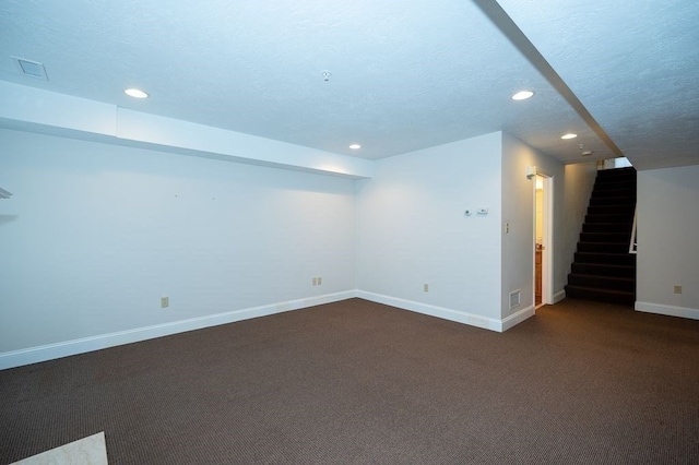 basement with a textured ceiling and dark colored carpet