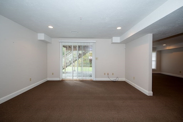 carpeted spare room featuring a textured ceiling and a healthy amount of sunlight