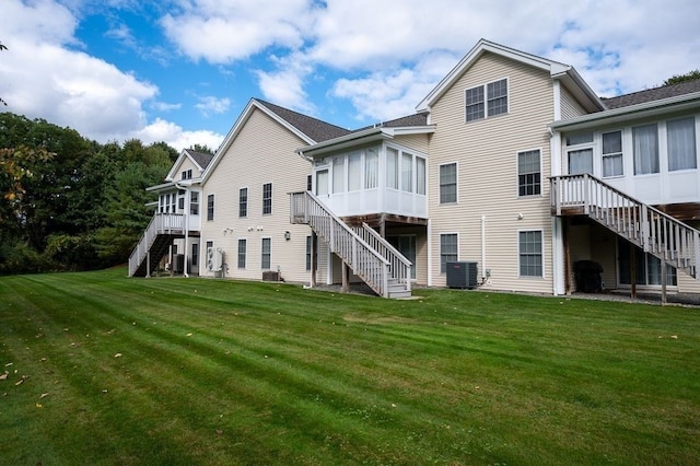 rear view of property featuring a wooden deck, a yard, and central AC