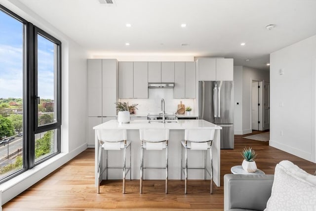 1515 Commonwealth Ave Unit 211, Boston, MA 02135 - kitchen featuring freestanding refrigerator, under cabinet range hood, light countertops, a center island with sink, and plenty of natural light