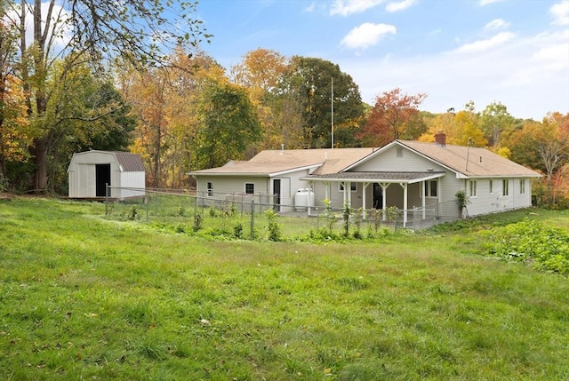 back of property with a shed and a yard