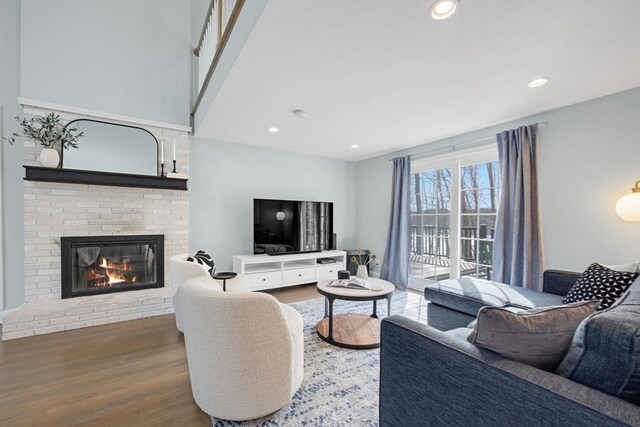 living room with recessed lighting, a brick fireplace, and wood finished floors