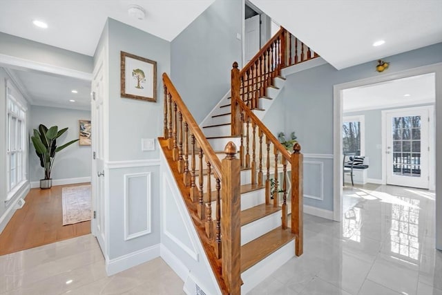 stairway with a decorative wall, plenty of natural light, and recessed lighting