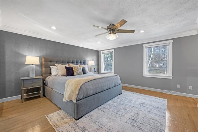 bedroom with crown molding, wood finished floors, visible vents, and baseboards