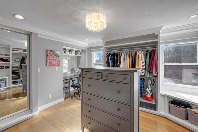 walk in closet featuring an inviting chandelier and light wood-style floors