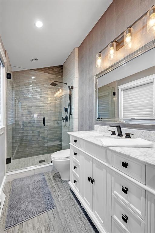 full bathroom with vanity, a shower stall, and toilet