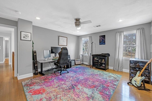 office featuring visible vents, a ceiling fan, baseboards, and wood finished floors