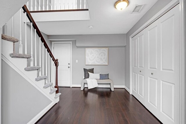 entrance foyer featuring visible vents, baseboards, dark wood-style floors, and stairs