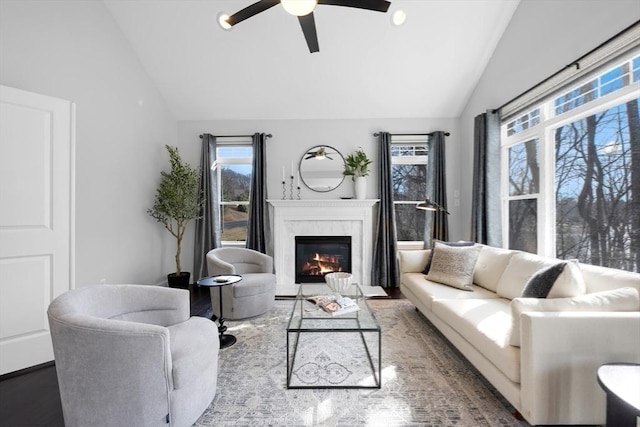 living area with lofted ceiling, wood finished floors, a ceiling fan, and a high end fireplace