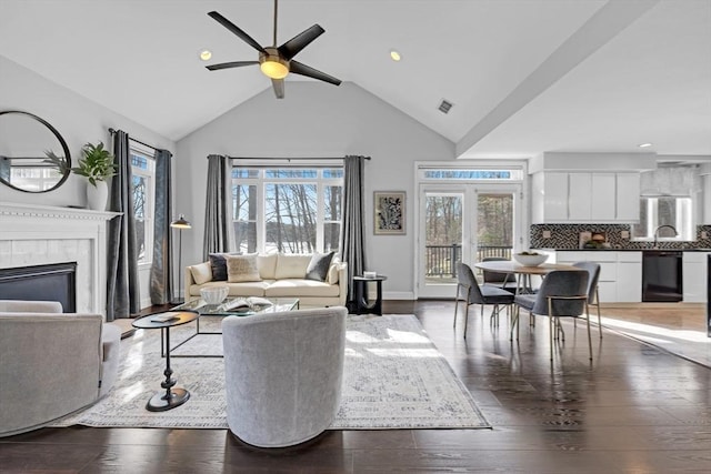 living room with visible vents, plenty of natural light, wood-type flooring, and a glass covered fireplace