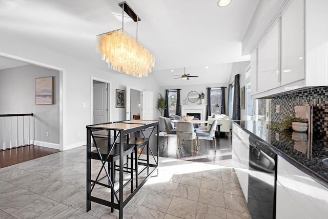 kitchen featuring dishwasher, vaulted ceiling, a fireplace, white cabinets, and marble finish floor