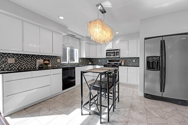 kitchen featuring dark countertops, backsplash, appliances with stainless steel finishes, marble finish floor, and white cabinetry