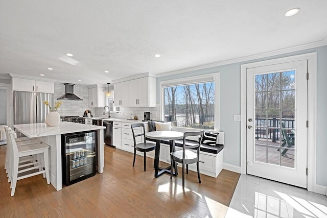 dining room with beverage cooler, baseboards, recessed lighting, crown molding, and light wood-type flooring