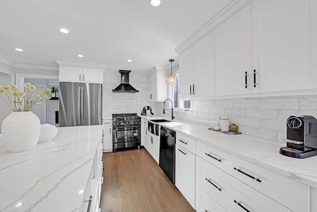 kitchen with black appliances, a sink, white cabinets, crown molding, and wall chimney range hood