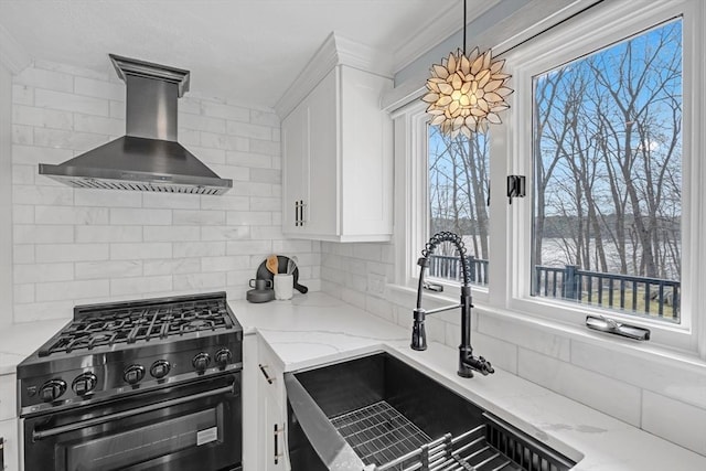 kitchen with a sink, black range with gas stovetop, white cabinetry, wall chimney range hood, and tasteful backsplash