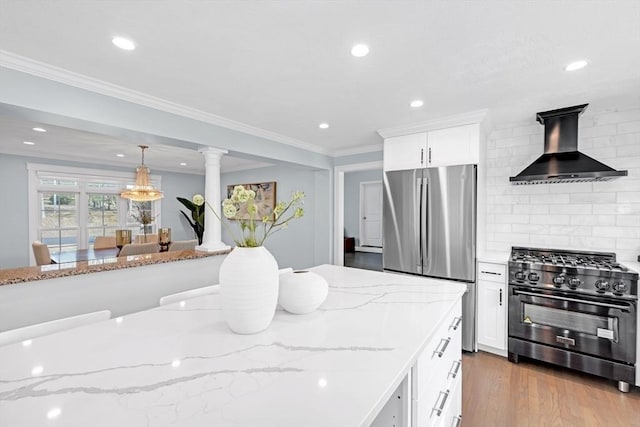 kitchen featuring ornamental molding, decorative backsplash, wood finished floors, stainless steel appliances, and wall chimney exhaust hood