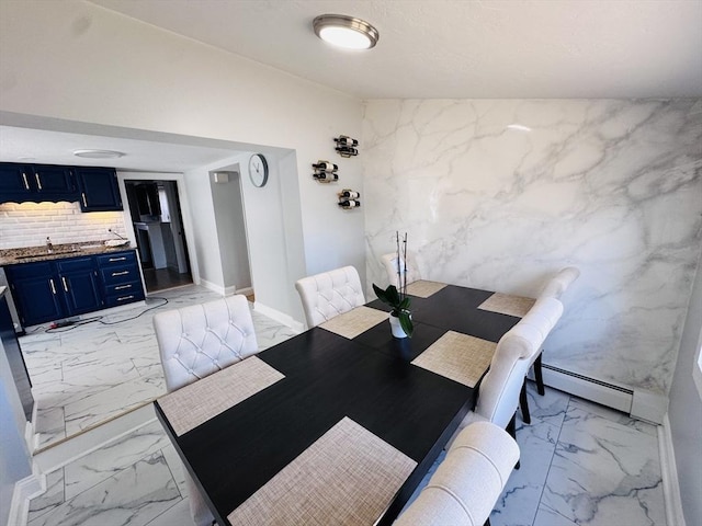 unfurnished dining area featuring a baseboard radiator, baseboards, marble finish floor, and a sink