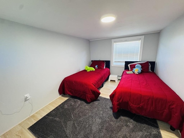 bedroom featuring a baseboard heating unit, wood finished floors, and a baseboard radiator