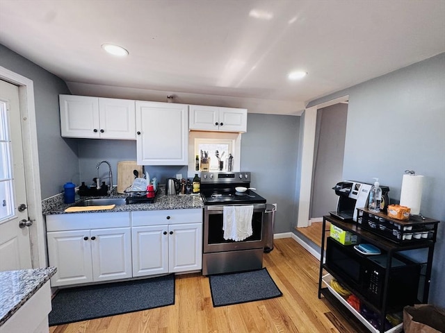 kitchen with stainless steel electric range oven, stone countertops, a sink, light wood-style floors, and white cabinetry