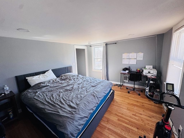 bedroom featuring light wood finished floors and baseboards