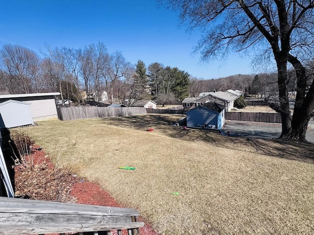 view of yard featuring an outbuilding, fence, and a shed