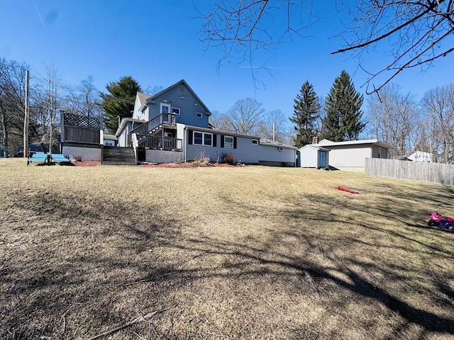 exterior space featuring a lawn, an outdoor structure, stairs, and fence