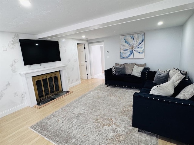 living area featuring a glass covered fireplace, recessed lighting, wood finished floors, and baseboards