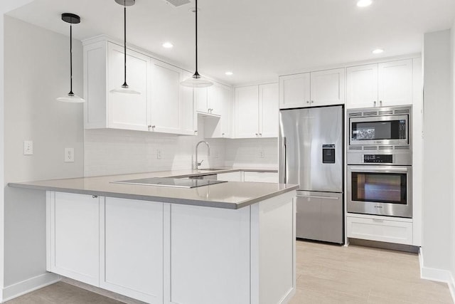 kitchen featuring pendant lighting, kitchen peninsula, white cabinets, and appliances with stainless steel finishes