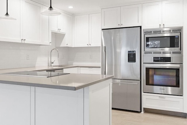 kitchen with sink, tasteful backsplash, hanging light fixtures, appliances with stainless steel finishes, and white cabinets