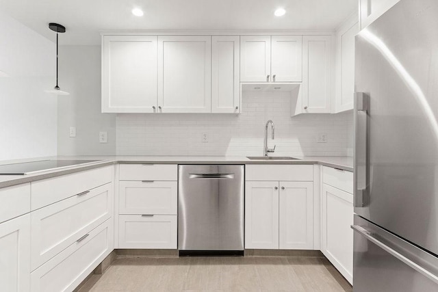 kitchen featuring hanging light fixtures, appliances with stainless steel finishes, sink, and white cabinets